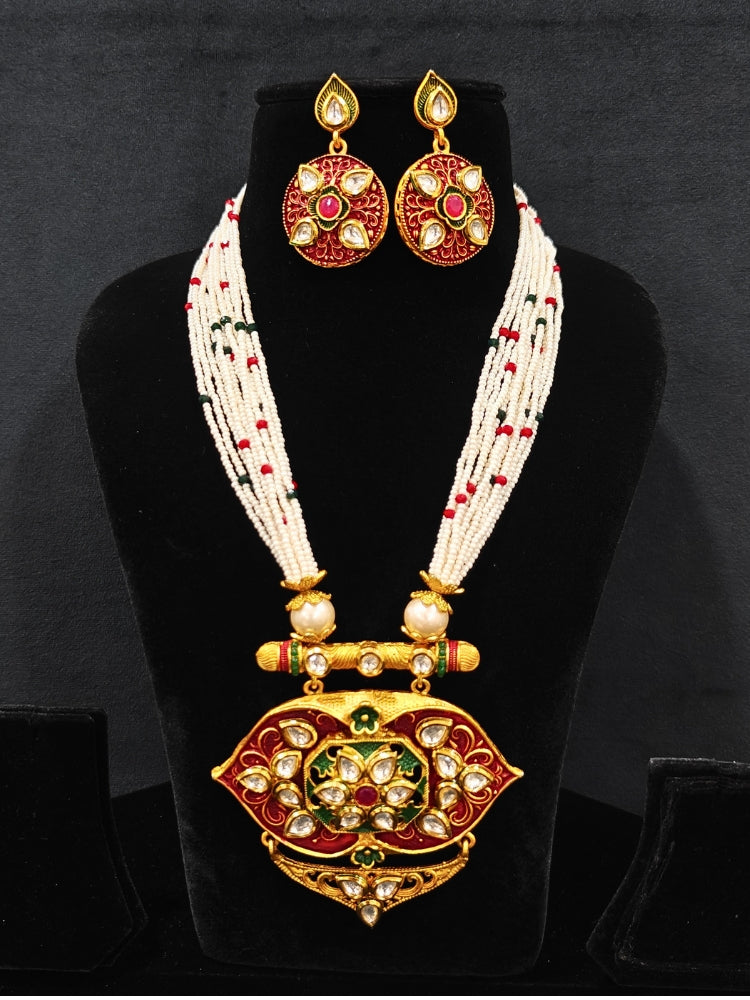 Close-up of a woman wearing an ornate traditional Red Rajwadi gold jewellery set and earrings  with  Kundan, Meenakari, Pearls, Crystal Beads, Ruby Red Colored Stones. Mehendi ceremony look styled with a Rajwadi and Meenakari artificial jewelry set. Model wearing a royal Rajwadi and Meenakari necklace set for festive celebrations in India.