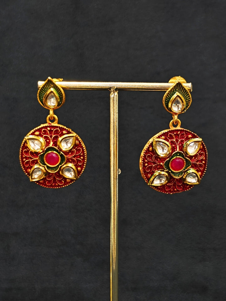 Close-up of a woman wearing an ornate traditional Red Rajwadi gold jewellery set and earrings  with  Kundan, Meenakari, Pearls, Crystal Beads, Ruby Red Colored Stones. Mehendi ceremony look styled with a Rajwadi and Meenakari artificial jewelry set. Model wearing a royal Rajwadi and Meenakari necklace set for festive celebrations in India.