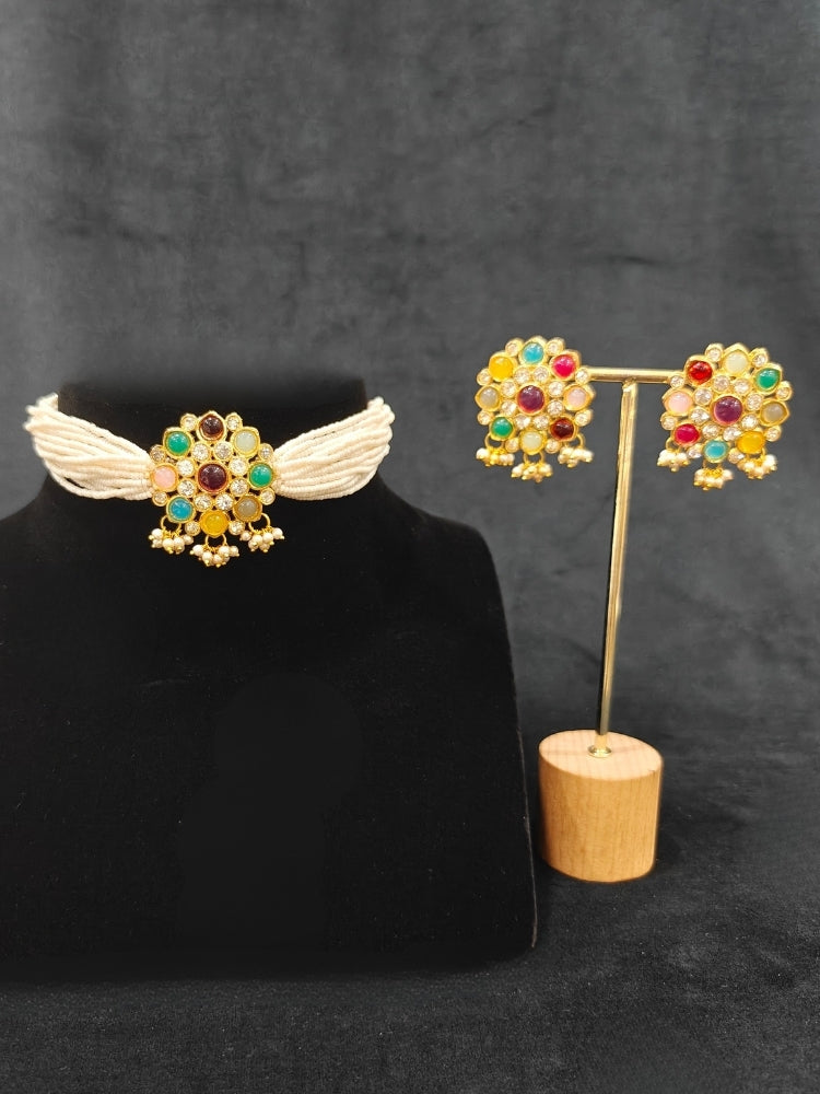 Close-up of an ornate traditional (Gold Polish) Choker jewellery set and earrings with American Damonds,  Multi-Colored Stones and Pearls. Mehendi ceremony look completed with a handcrafted Colored Stone jewelry set. Festive Diwali outfit paired with a colorful  Colored Stones necklace.