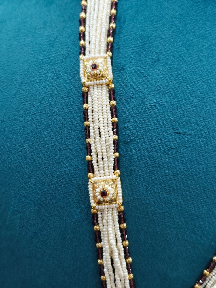 Close-up of an ornate traditional Purple Rajwadi gold Long jewellery set and earrings with Pearls, Crystal beads, American Diamonds, Colored Stones and Meenakari work.  Elegant Anarkali look paired with a traditional Rajwadi artificial necklace. Wedding guest styling a Rajwadi artificial necklace. 