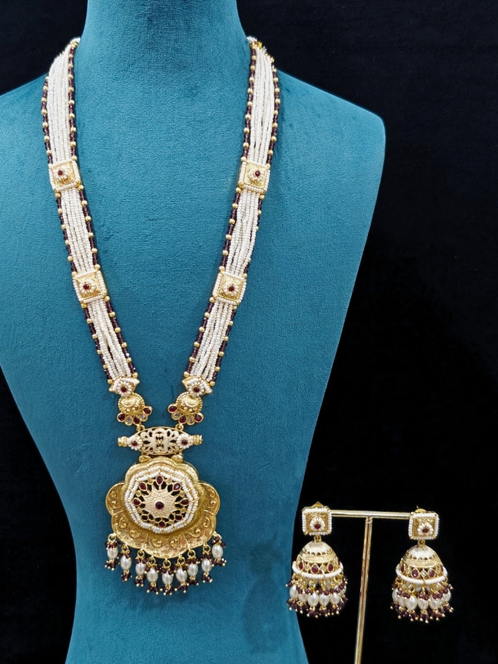 Close-up of an ornate traditional Purple Rajwadi gold Long jewellery set and earrings with Pearls, Crystal beads, American Diamonds, Colored Stones and Meenakari work.  Elegant Anarkali look paired with a traditional Rajwadi artificial necklace. Wedding guest styling a Rajwadi artificial necklace. 