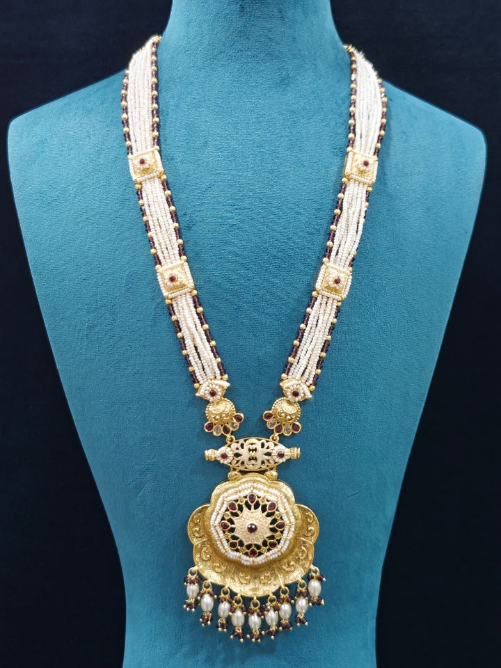 Close-up of an ornate traditional Purple Rajwadi gold Long jewellery set and earrings with Pearls, Crystal beads, American Diamonds, Colored Stones and Meenakari work.  Elegant Anarkali look paired with a traditional Rajwadi artificial necklace. Wedding guest styling a Rajwadi artificial necklace. 