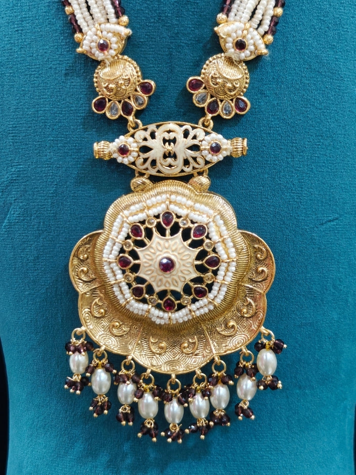 Close-up of an ornate traditional Purple Rajwadi gold Long jewellery set and earrings with Pearls, Crystal beads, American Diamonds, Colored Stones and Meenakari work.  Elegant Anarkali look paired with a traditional Rajwadi artificial necklace. Wedding guest styling a Rajwadi artificial necklace. 