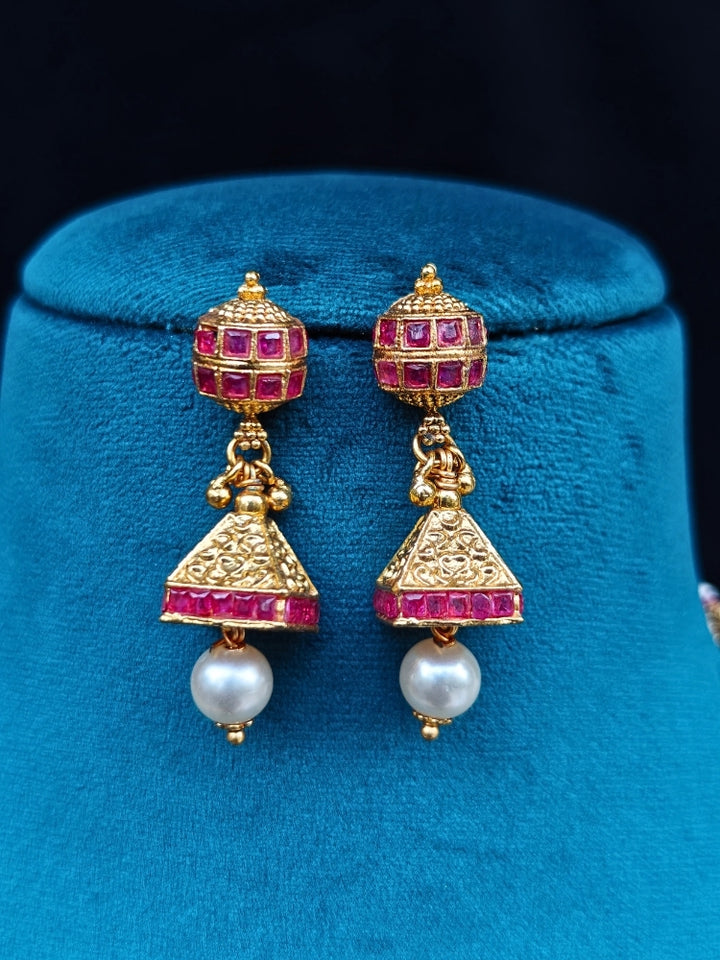 Close-up of an ornate traditional (Gold Polish) Long jewellery set and earrings with Pearls and Colored Stone. Mehendi function outfit styled with a lightweight Pearl necklace. Woman pairing a traditional Pearl necklace with a silk saree.