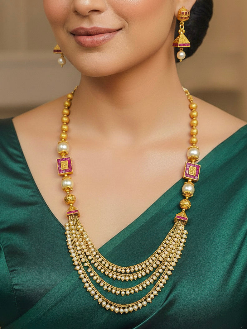 Close-up of a woman wearing an ornate traditional (Gold Polish) Long jewellery set and earrings with Pearls and Colored Stone. Mehendi function outfit styled with a lightweight Pearl necklace. Woman pairing a traditional Pearl necklace with a silk saree.