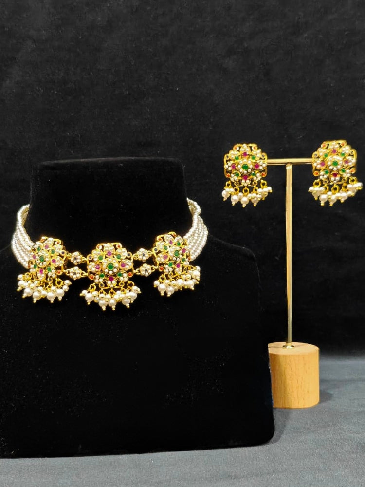 Close-up of an ornate traditional Navratan Choker jadau gold jewellery set and  jadau earrings with Pearl and Navratan Colored Stone. Festive celebration look featuring a Jadau artificial necklace. Close-up of intricate Jadau detailing in bridal jewelry.