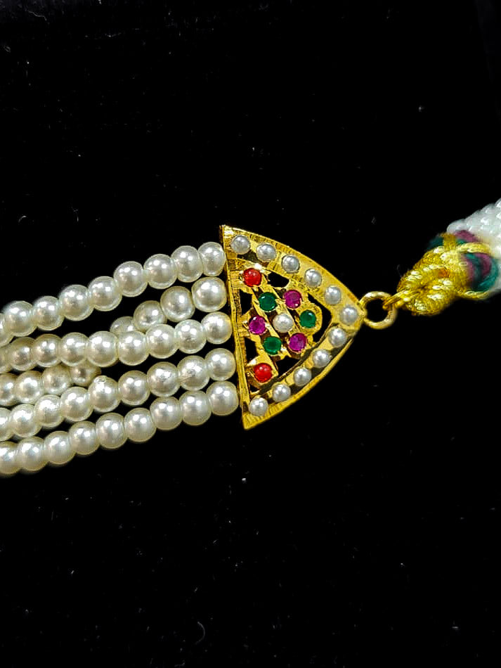 Close-up of an ornate traditional Navratan Choker jadau gold jewellery set and  jadau earrings with Pearl and Navratan Colored Stone. Festive celebration look featuring a Jadau artificial necklace. Close-up of intricate Jadau detailing in bridal jewelry.