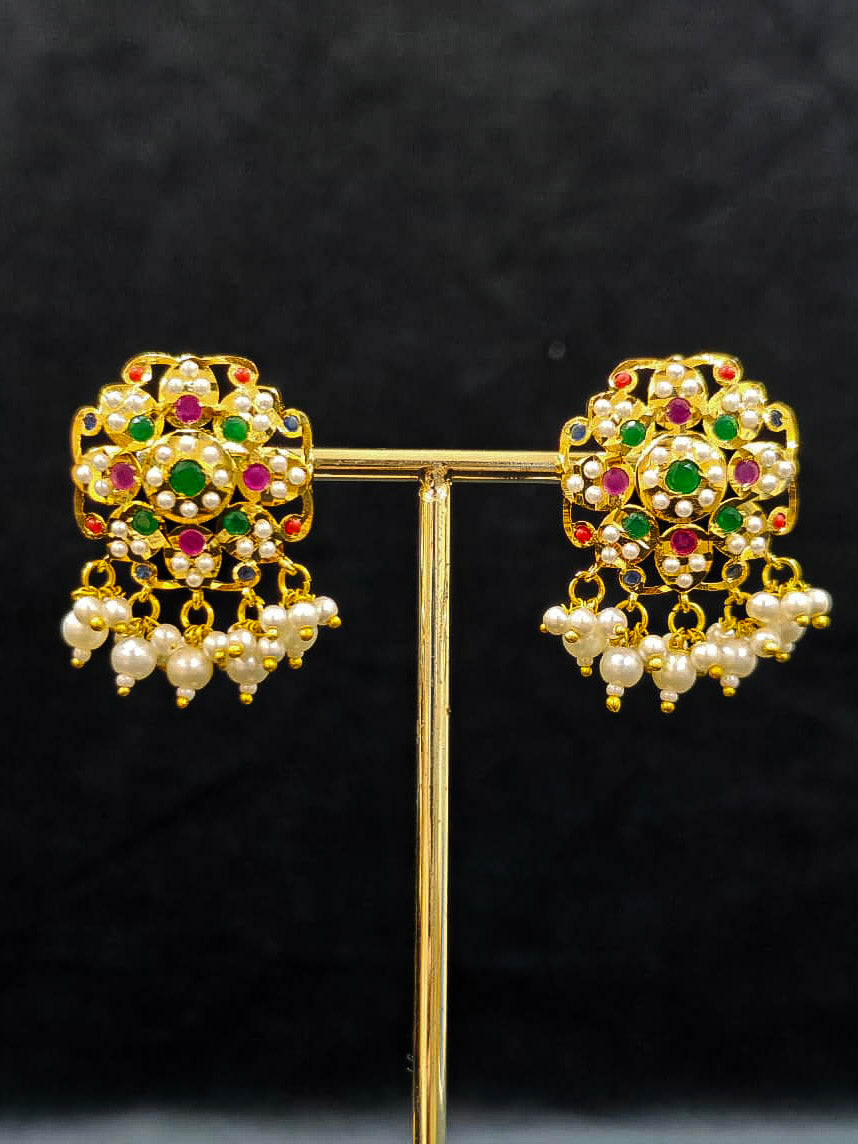 Close-up of an ornate traditional Navratan Choker jadau gold jewellery set and  jadau earrings with Pearl and Navratan Colored Stone. Festive celebration look featuring a Jadau artificial necklace. Close-up of intricate Jadau detailing in bridal jewelry.