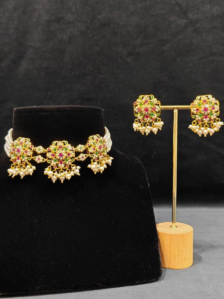 Close-up of an ornate traditional Ruby Pink and Green Choker jadau gold jewellery set and  jadau earrings with Pearl and Colored Stone. Festive look completed with a handcrafted Jadau necklace. A royal Jadau necklace for festive events in India.