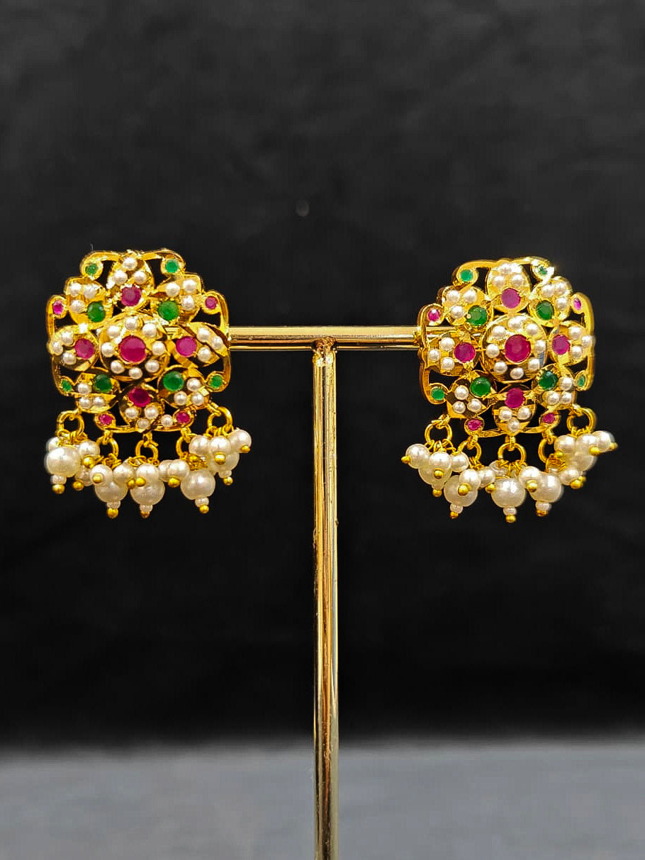 Close-up of an ornate traditional Ruby Pink and Green Choker jadau gold jewellery set and  jadau earrings with Pearl and Colored Stone. Festive look completed with a handcrafted Jadau necklace. A royal Jadau necklace for festive events in India.
