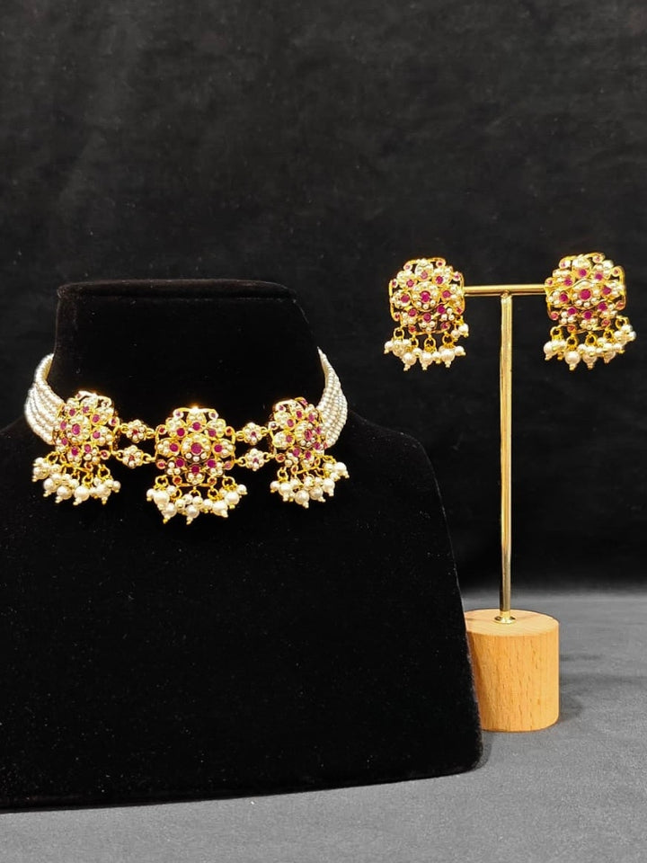 Close-up of an ornate traditional Ruby Pink Choker jadau gold jewellery set and  jadau earrings with Pearl and Colored Stone. Close-up of high-quality Jadau artificial necklace craftsmanship. Close-up of intricate Jadau detailing in artificial jewelry.