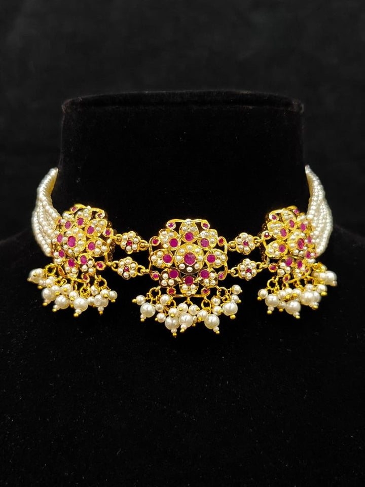 Close-up of an ornate traditional Ruby Pink Choker jadau gold jewellery set and  jadau earrings with Pearl and Colored Stone. Close-up of high-quality Jadau artificial necklace craftsmanship. Close-up of intricate Jadau detailing in artificial jewelry.