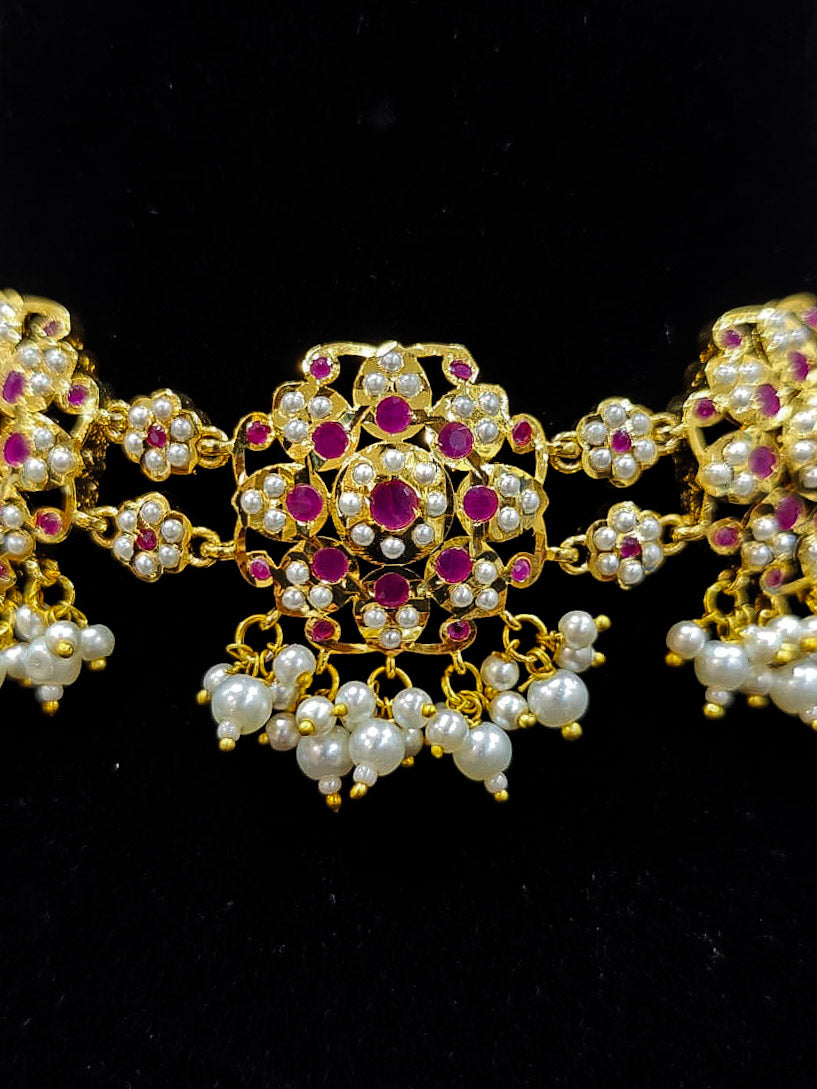 Close-up of an ornate traditional Ruby Pink Choker jadau gold jewellery set and  jadau earrings with Pearl and Colored Stone. Close-up of high-quality Jadau artificial necklace craftsmanship. Close-up of intricate Jadau detailing in artificial jewelry.