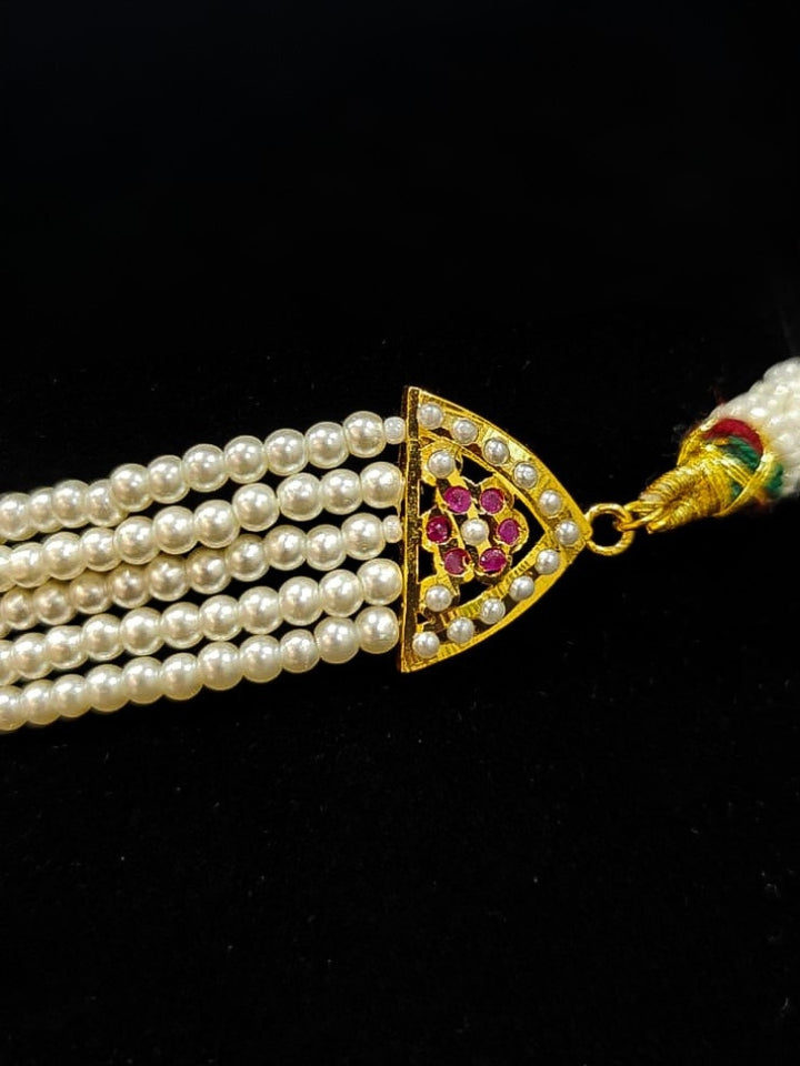 Close-up of an ornate traditional Ruby Pink Choker jadau gold jewellery set and  jadau earrings with Pearl and Colored Stone. Close-up of high-quality Jadau artificial necklace craftsmanship. Close-up of intricate Jadau detailing in artificial jewelry.