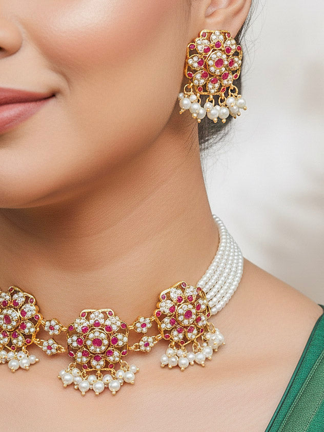 Close-up of a woman wearing a gold Indian traditional jadau jewellery with pearls and pink colored stones, and matching jadau earrings. This authentic jadau jewelry set can we worn as jadau necklace set for weddings. 