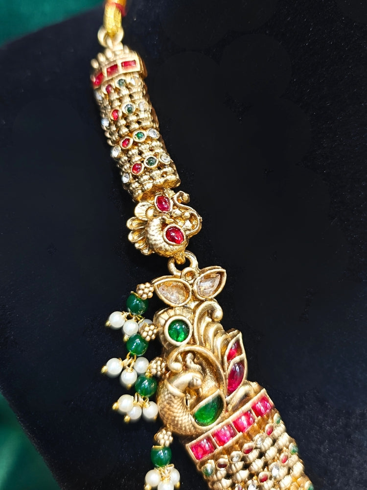 the Kantha Temple Necklace Set featuring a traditional gold Long necklace and matching earrings with Goddess Laxmi in the middle, along with pink and green colored stones, paired with Saree —Bride showcasing a premium temple artificial jewelry set for wedding rituals.