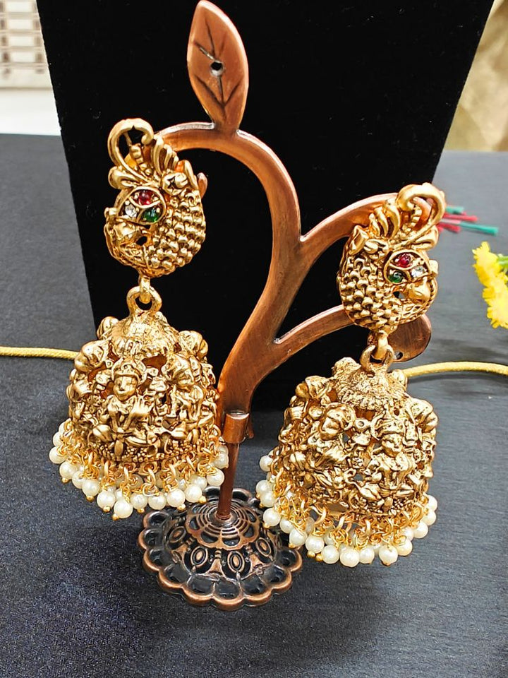 The Kantha Temple Necklace Set featuring a traditional gold Long necklace and matching earrings with Goddess Laxmi in the middle, along with pink and green colored stones, paired with Saree —Close-up of detailed temple carvings in artificial wedding jewelry.