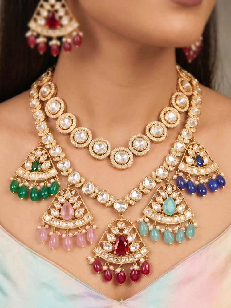 Close-up of a woman wearing an ornate traditional (Gold Polish) Layered Multi-Color jewellery set and earrings with Polki, American Diamond, Colored Stones and Tumble Beads. Woman styling a premium Polki imitation necklace for wedding celebrations. Festive celebration look completed with premium imitation Polki jewelry.