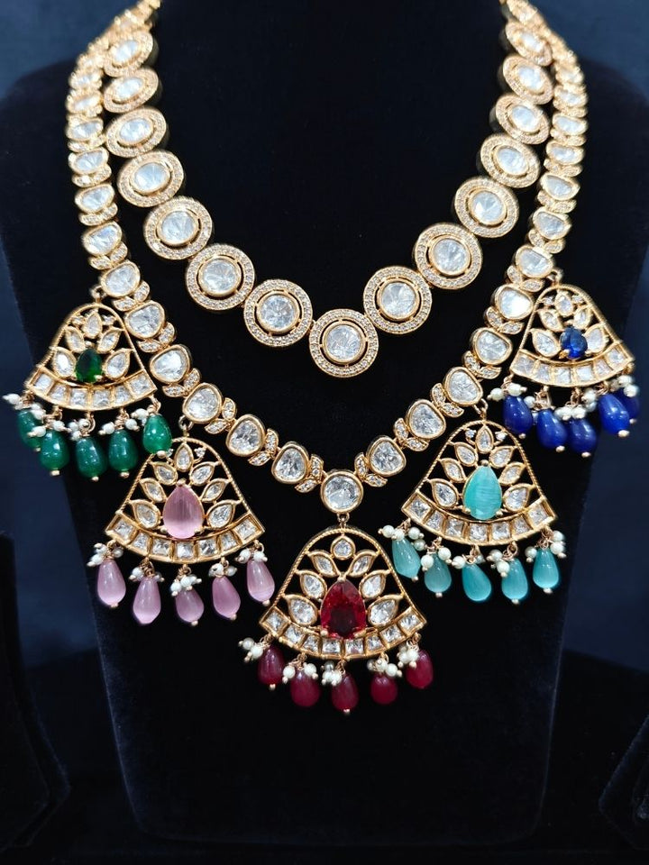 Close-up of an ornate traditional (Gold Polish) Layered Multi-Color jewellery set and earrings with Polki, American Diamond, Colored Stones and Tumble Beads. Woman styling a premium Polki imitation necklace for wedding celebrations. Festive celebration look completed with premium imitation Polki jewelry.