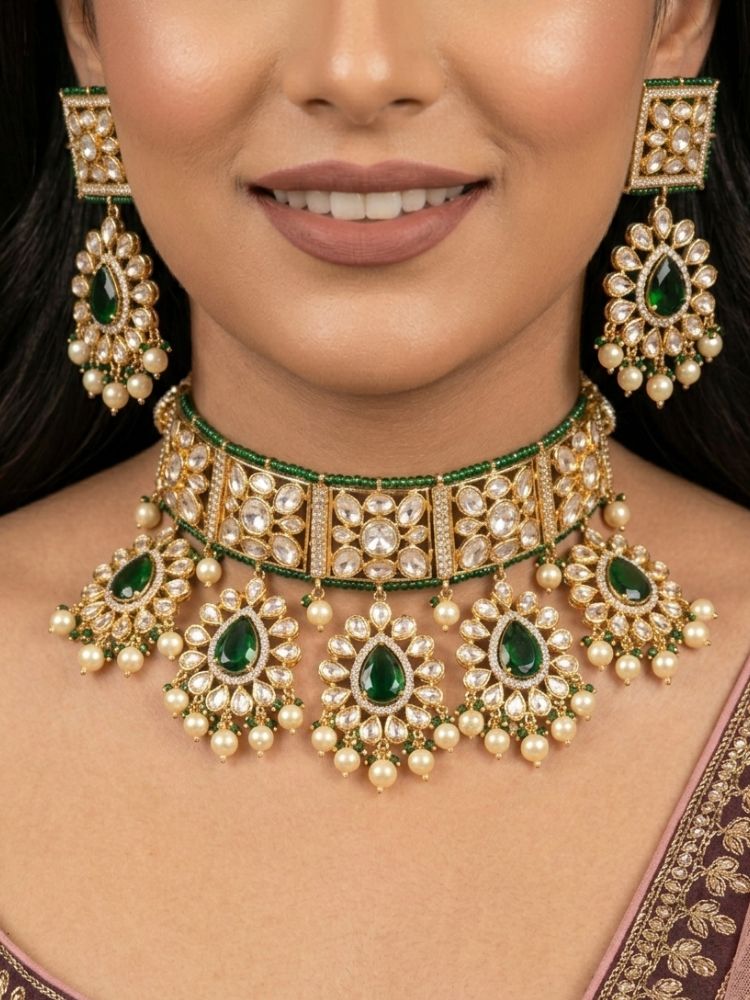 Close-up of a woman wearing an ornate traditional (Gold Polish) Dark Green Choker jewellery set and earrings and maangtikka with Polki, Pearl, Dark Green Colored Stones and Crystal Beads. Woman styling a premium Polki imitation necklace for wedding celebrations. Woman wearing a lightweight Polki jewelry set for long wedding functions.