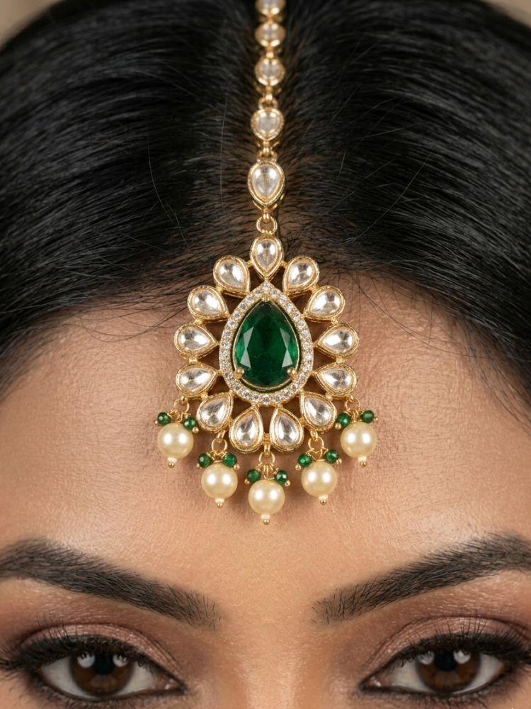 Close-up of a woman wearing an ornate traditional (Gold Polish) Dark Green Choker jewellery set and earrings and maangtikka with Polki, Pearl, Dark Green Colored Stones and Crystal Beads. Woman styling a premium Polki imitation necklace for wedding celebrations. Woman wearing a lightweight Polki jewelry set for long wedding functions.