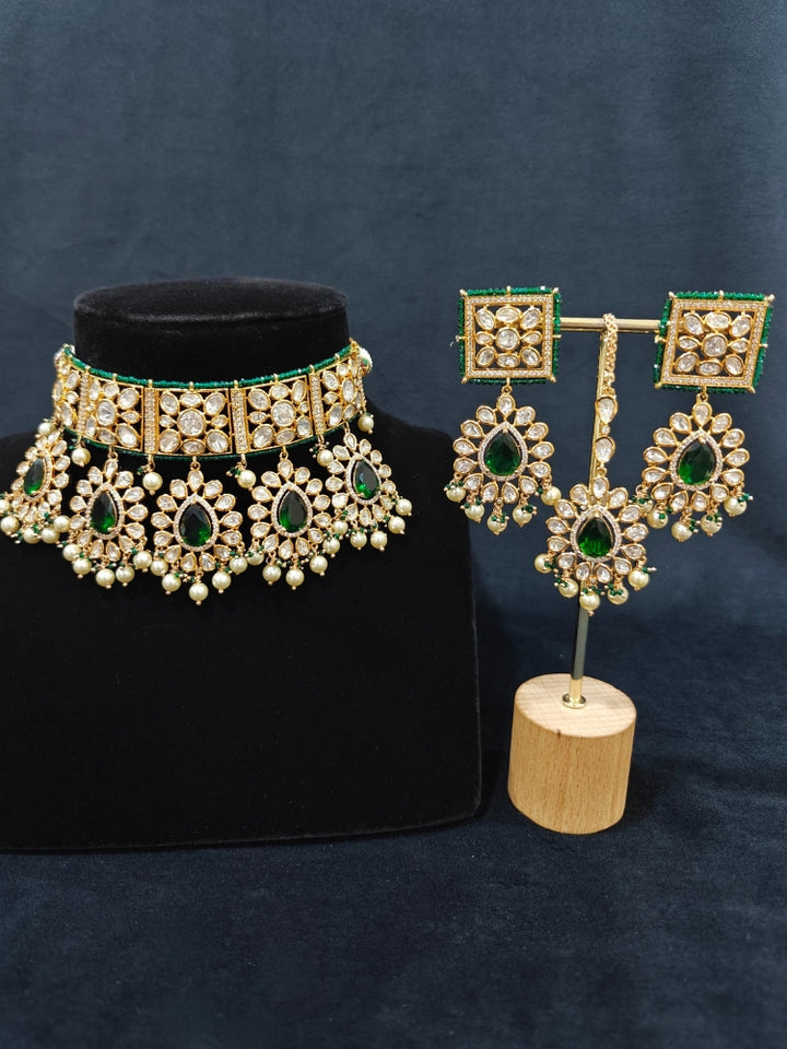 Close-up of an ornate traditional (Gold Polish) Dark Green Choker jewellery set and earrings and maangtikka with Polki, Pearl, Dark Green Colored Stones and Crystal Beads. Woman styling a premium Polki imitation necklace for wedding celebrations. Woman wearing a lightweight Polki jewelry set for long wedding functions.