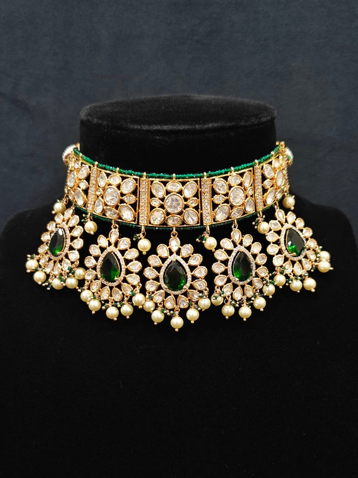 Close-up of an ornate traditional (Gold Polish) Dark Green Choker jewellery set and earrings and maangtikka with Polki, Pearl, Dark Green Colored Stones and Crystal Beads. Woman styling a premium Polki imitation necklace for wedding celebrations. Woman wearing a lightweight Polki jewelry set for long wedding functions.