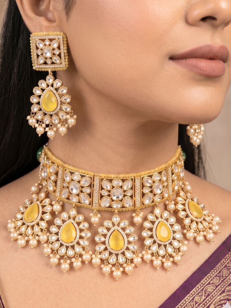 Close-up of a woman wearing an ornate traditional (Gold Polish) Yellow Choker jewellery set and earrings and maangtikka with Polki, Pearl, Yellow Colored Stones and Crystal Beads. Woman styling a premium Polki imitation necklace for wedding celebrations. Woman wearing a lightweight Polki jewelry set for long wedding functions.