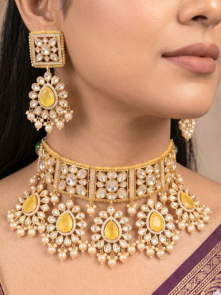 Close-up of a woman wearing an ornate traditional (Gold Polish) Yellow Choker jewellery set and earrings and maangtikka with Polki, Pearl, Yellow Colored Stones and Crystal Beads. Woman styling a premium Polki imitation necklace for wedding celebrations. Woman wearing a lightweight Polki jewelry set for long wedding functions.