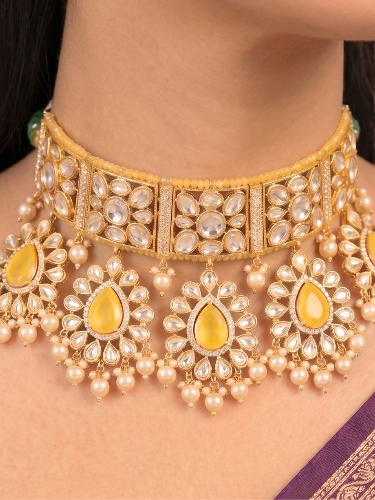 Close-up of a woman wearing an ornate traditional (Gold Polish) Yellow Choker jewellery set and earrings and maangtikka with Polki, Pearl, Yellow Colored Stones and Crystal Beads. Woman styling a premium Polki imitation necklace for wedding celebrations. Woman wearing a lightweight Polki jewelry set for long wedding functions.