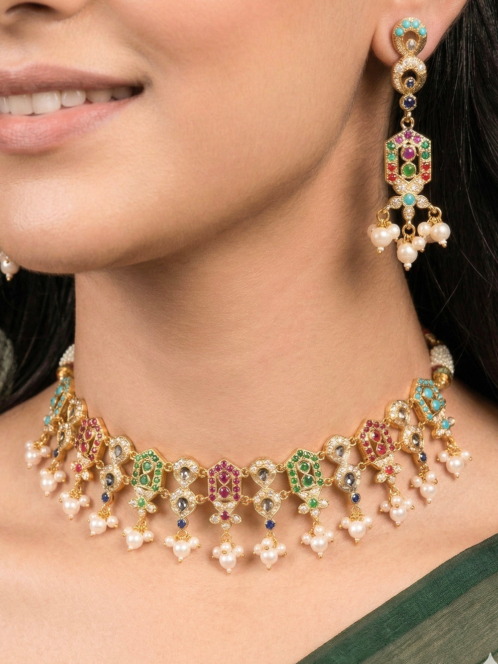 Close-up of a woman wearing an ornate traditional Navratan jadau gold jewellery set and jadau earrings with navratan color stone and Pearls. Woman pairing a traditional Jadau necklace with a silk saree. Woman wearing a royal Jadau necklace for festive events in India.