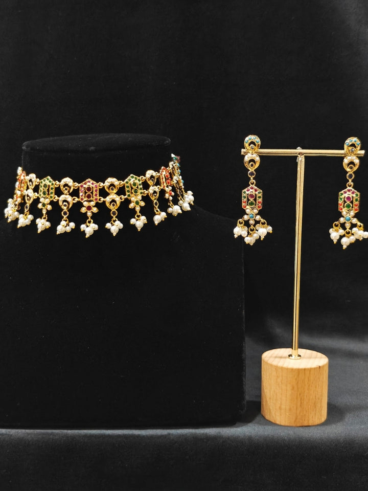 Close-up of an ornate traditional Navratan jadau gold jewellery set and jadau earrings with navratan color stone and Pearls. Elegant reception look featuring a luxury Jadau artificial jewelry set. Festive celebration look featuring a Jadau artificial necklace.