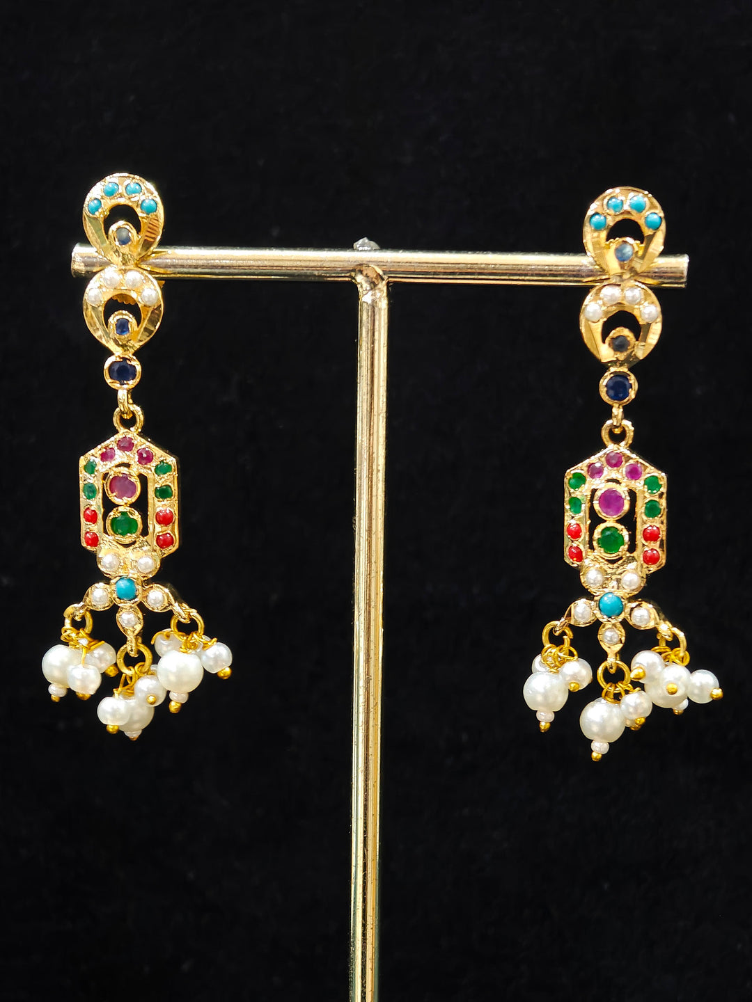 Close-up of an ornate traditional Navratan jadau gold jewellery set and jadau earrings with navratan color stone and Pearls. Elegant reception look featuring a luxury Jadau artificial jewelry set. Festive celebration look featuring a Jadau artificial necklace.
