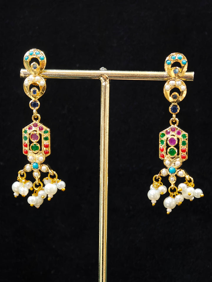 Close-up of an ornate traditional Navratan jadau gold jewellery set and jadau earrings with navratan color stone and Pearls. Elegant reception look featuring a luxury Jadau artificial jewelry set. Festive celebration look featuring a Jadau artificial necklace.