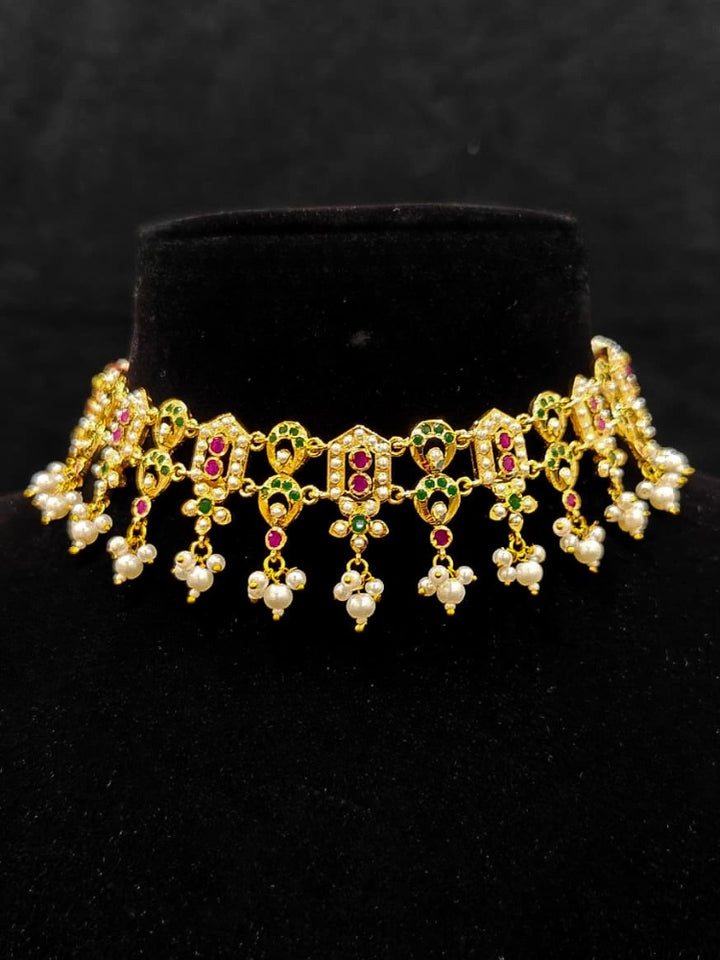 Close-up of a gold Indian traditional jadau jewellery with pearls and ruby pink and green jadau stones. This authentic jadau jewelry set can we worn as jadau necklace set for weddings. a royal Jadau necklace for festive events in India.