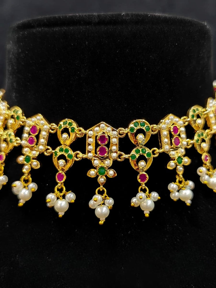 Close-up of a gold Indian traditional jadau jewellery with pearls and ruby pink and green jadau stones. This authentic jadau jewelry set can we worn as jadau necklace set for weddings. a royal Jadau necklace for festive events in India.