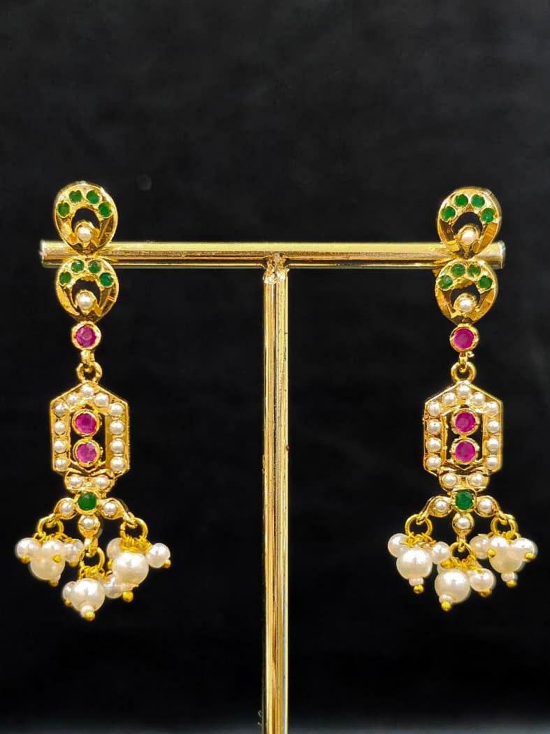 Close-up of a gold Indian traditional jadau jewellery with pearls and ruby pink and green jadau stones. This authentic jadau jewelry set can we worn as jadau necklace set for weddings. a royal Jadau necklace for festive events in India.