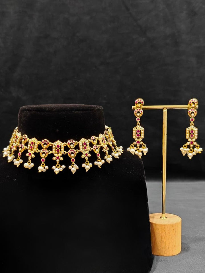 Close-up of an ornate traditional Ruby Pink jadau gold jewellery set and jadau earrings with Pearls and gemstones. Festive celebration look featuring a Jadau artificial necklace. Elegant reception look featuring a luxury Jadau artificial jewelry set.