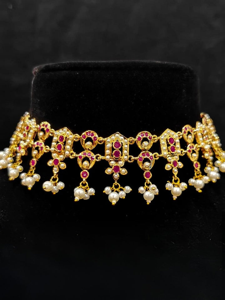 Close-up of an ornate traditional Ruby Pink jadau gold jewellery set and jadau earrings with Pearls and gemstones. Festive celebration look featuring a Jadau artificial necklace. Elegant reception look featuring a luxury Jadau artificial jewelry set.