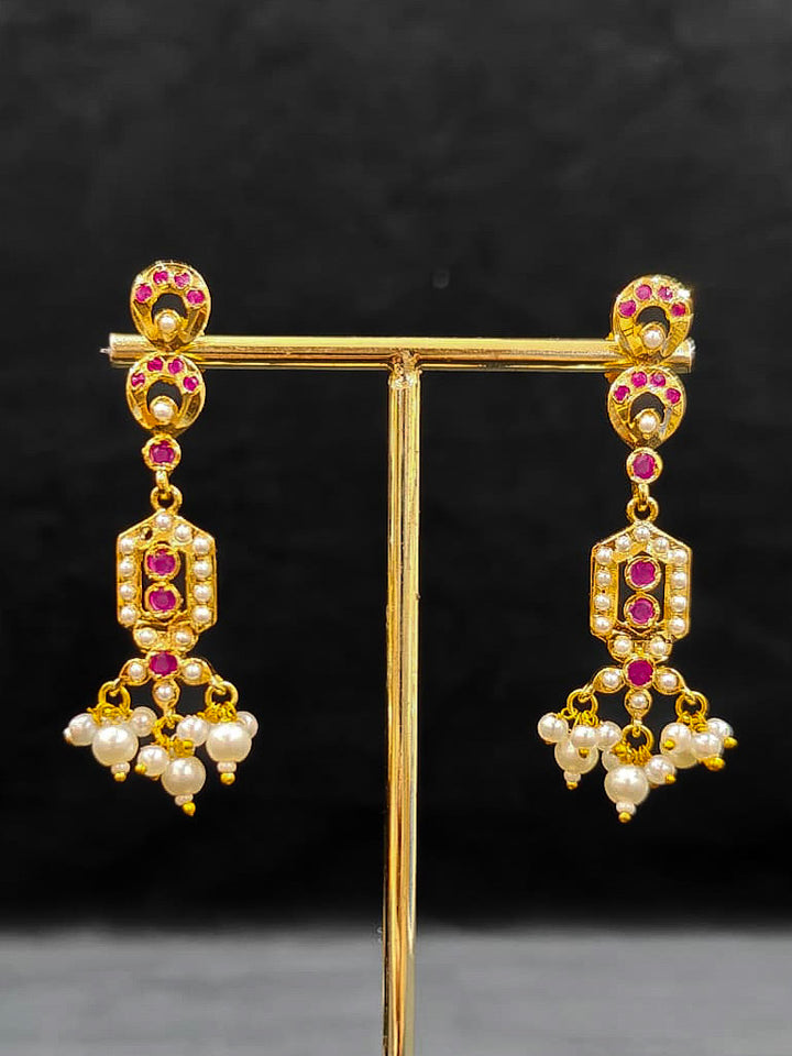 Close-up of an ornate traditional Ruby Pink jadau gold jewellery set and jadau earrings with Pearls and gemstones. Festive celebration look featuring a Jadau artificial necklace. Elegant reception look featuring a luxury Jadau artificial jewelry set.