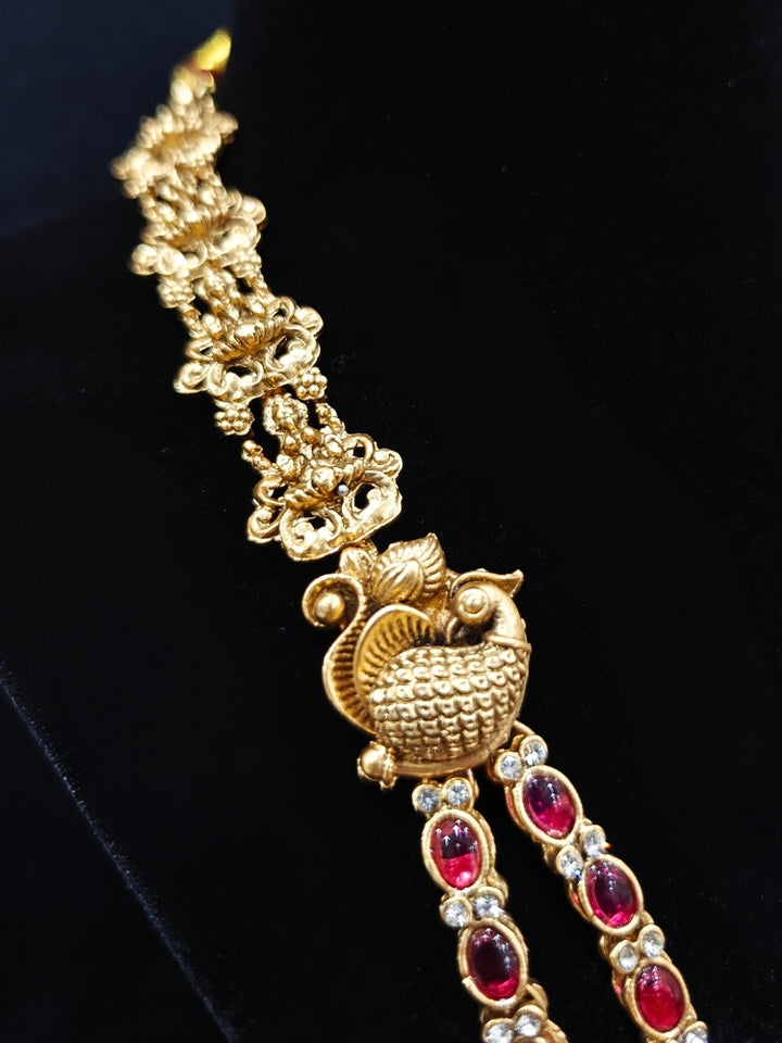 the Red Karuna Temple Necklace Set featuring a traditional gold Long necklace and matching earrings with Red colored stones, paired with a Saree—Saree look enhanced with a royal temple imitation necklace.