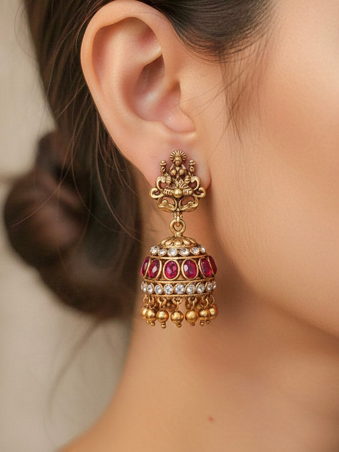 A woman wearing the Red Karuna Temple Necklace Set featuring a traditional gold Long necklace and matching earrings with Red colored stones, paired with a Saree—Saree look enhanced with a royal temple imitation necklace.