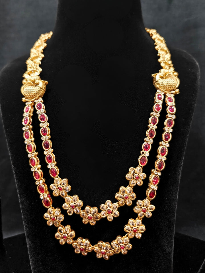 the Red Karuna Temple Necklace Set featuring a traditional gold Long necklace and matching earrings with Red colored stones, paired with a Saree—Saree look enhanced with a royal temple imitation necklace.