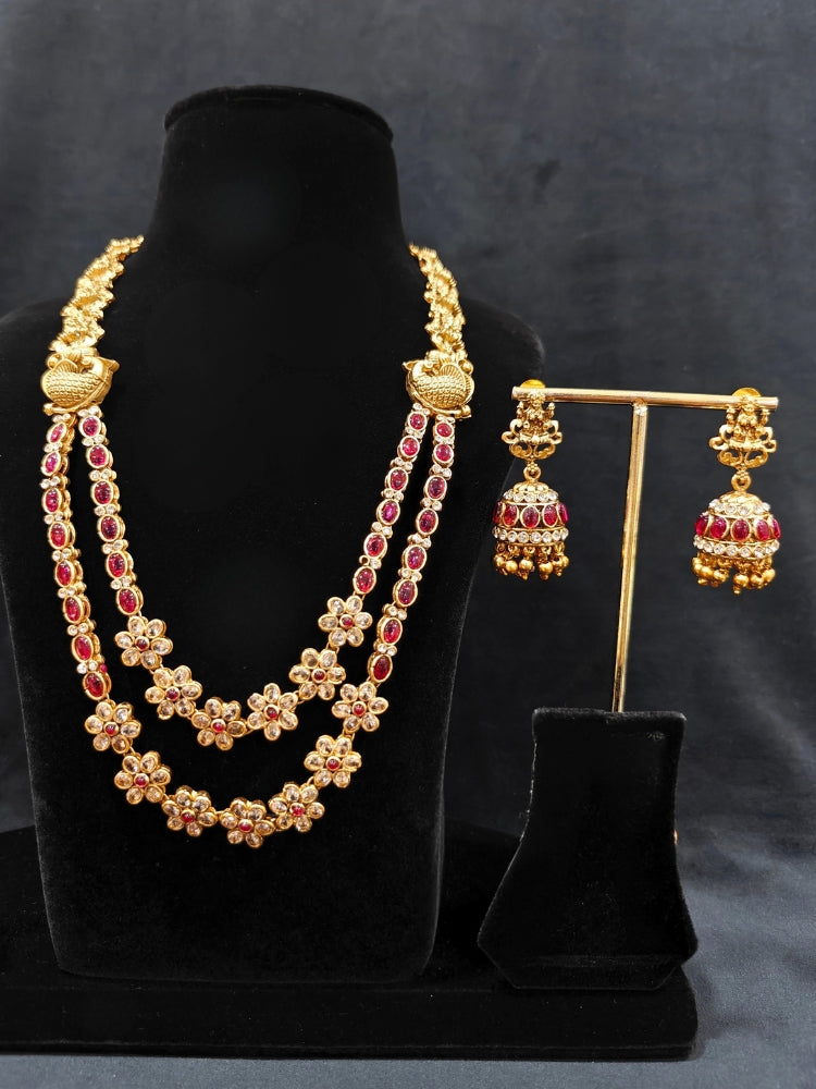 the Red Karuna Temple Necklace Set featuring a traditional gold Long necklace and matching earrings with Red colored stones, paired with a Saree—Saree look enhanced with a royal temple imitation necklace.