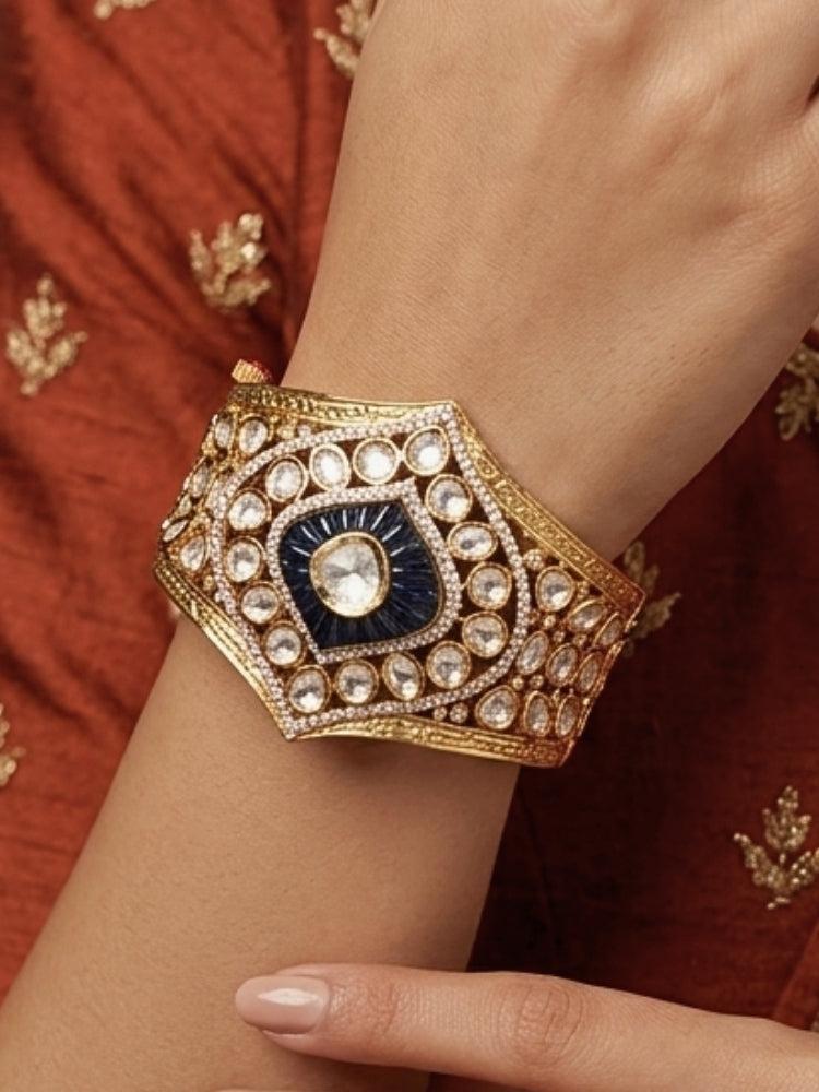 Close-up of a woman wearing an ornate traditional (Gold Polish) Navy Blue Bracelet with Polki, American Diamond and Navy Blue Colored Stone. Close-up of an anti-tarnish artificial Polki bracelet styled for wedding guests.Festive outfit paired with a premium imitation Polki bracelet in India.