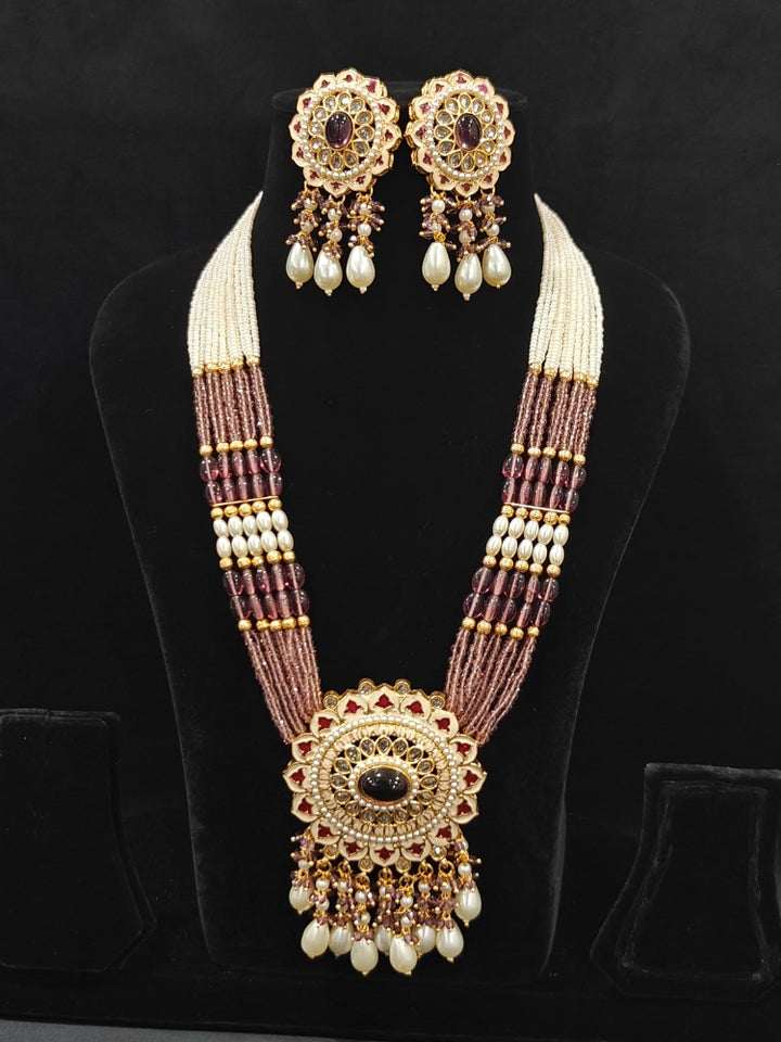 Close-up of an ornate traditional Lilac Rajwadi gold Long jewellery set and earrings with Pearls, Crystal beads, Tumble stones, American Diamonds, Colored Stones, Meenakari work and Pearls. Festive Diwali outfit enhanced with a Rajwadi artificial necklace. Royal wedding guest outfit featuring a Rajwadi necklace. Close-up of enamel work in Meenakari artificial wedding jewelry.