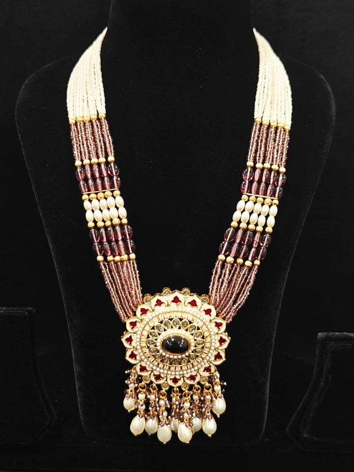 Close-up of an ornate traditional Lilac Rajwadi gold Long jewellery set and earrings with Pearls, Crystal beads, Tumble stones, American Diamonds, Colored Stones, Meenakari work and Pearls. Festive Diwali outfit enhanced with a Rajwadi artificial necklace. Royal wedding guest outfit featuring a Rajwadi necklace. Close-up of enamel work in Meenakari artificial wedding jewelry.
