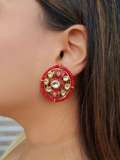 Close-up of a woman wearing an ornate traditional Red Kundan Studs Earrings with Kundan, Meenakari and Green Crystal Beads. Mehendi ceremony look completed with a handcrafted Kundan Earrings. Close-up of detailed enamel craftsmanship in Kundan Earrings.
