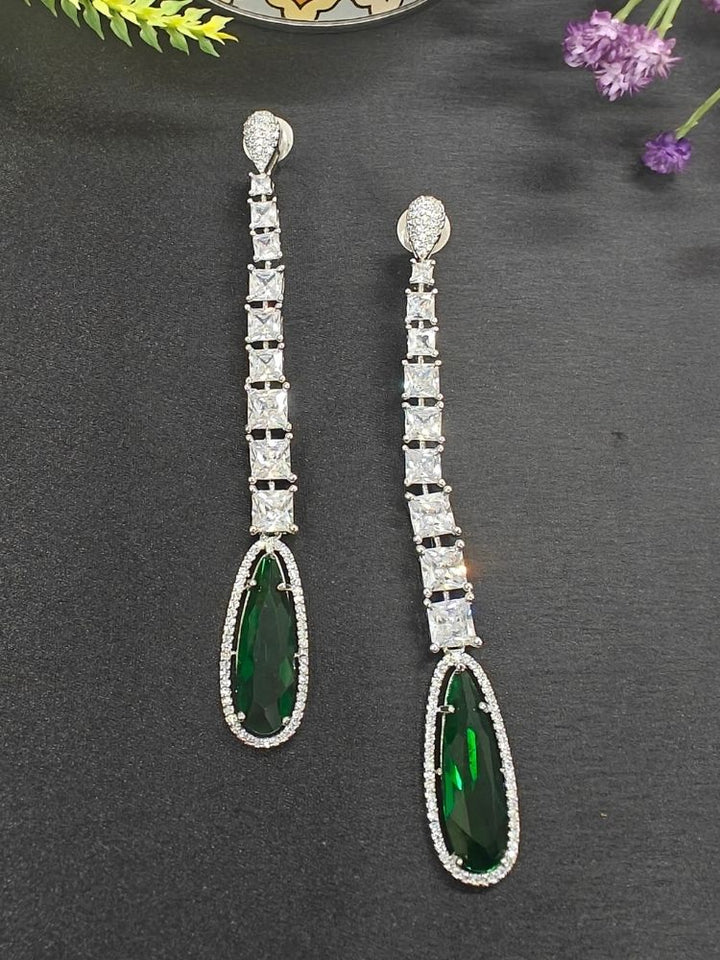 Kendall Green Earrings—long and elegant, set with four square American Diamonds and finished with a bold teardrop Green stone—ideal for enhancing a cocktail gown. Set on a black background. American Diamond Cocktail Earrings, American Diamond Earring. 
