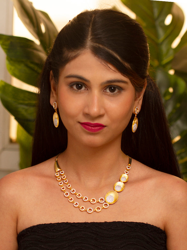 The Kensington Necklace Set is displayed in a box with a gold necklace featuring circular gold and silver accents, sparkling American Diamonds, and matching earrings—all set on black velvet with a satin gold border, perfect for parties.